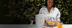 woman holding soup with prolon reset packaging on table 